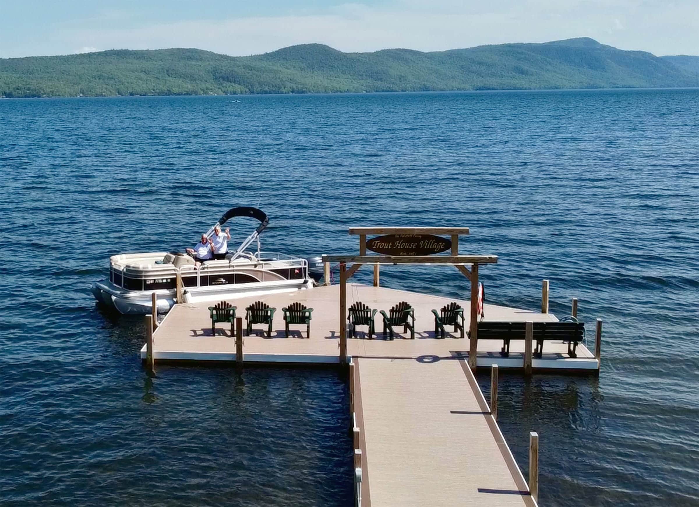 Pontoon boat docked at Trout House Village on Lake George with Adirondack mountains