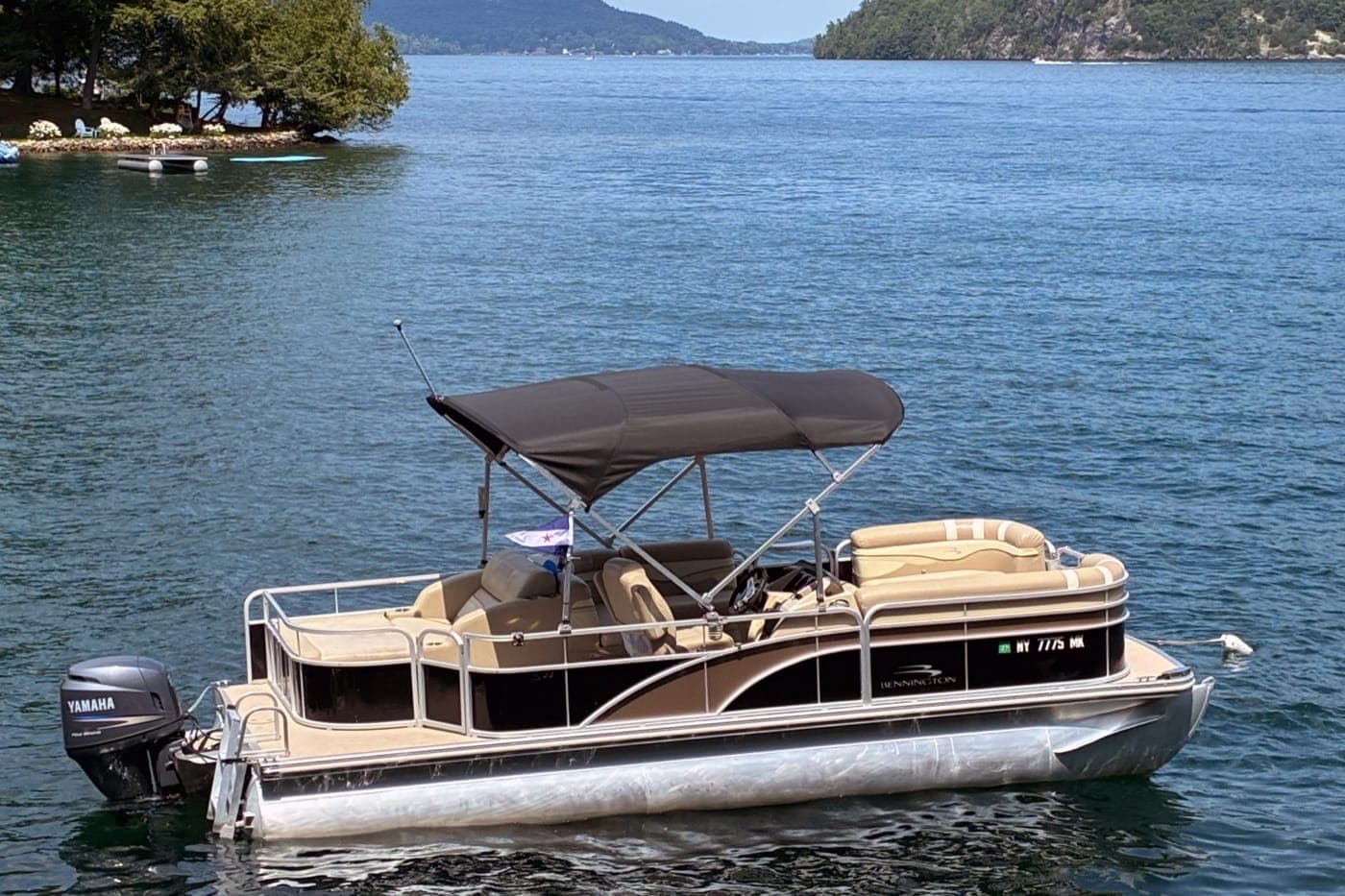 The pontoon boat anchored on Lake George with mountains in the background